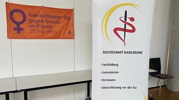 Plakat zum Tag gegen Gewalt an Frauen mit Rollup der Bezirksärztekammer Nordbaden 