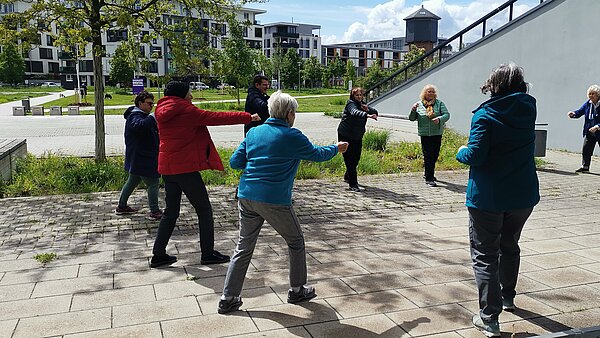 Personen stehen im City Park im Kreis und führen Koordinationsübungen durch
