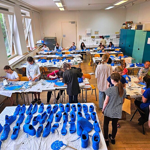 Schulkinder bemalen alte Schuhe blau