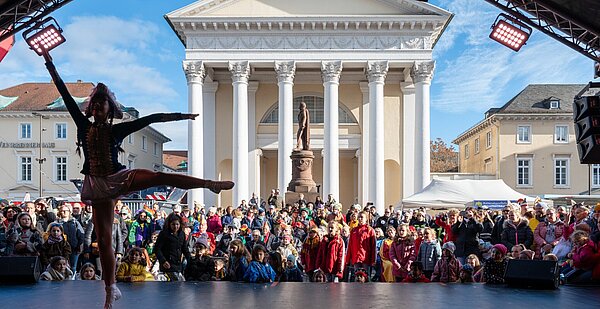 Rathaussturm 2023 Gardetänzerin auf einer Bühne, dahinter ist das Publikum und die Stadtkirche.