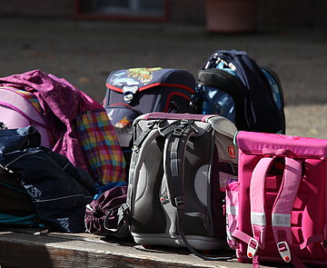 Schulranzen von Schulkindern Mehrere Schulranzen stehen auf einer Bank