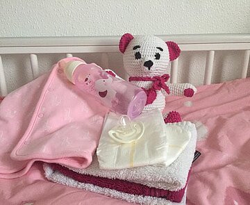 Babysachen Ein Spielzeugteddy liegt in einem Kinderbett.