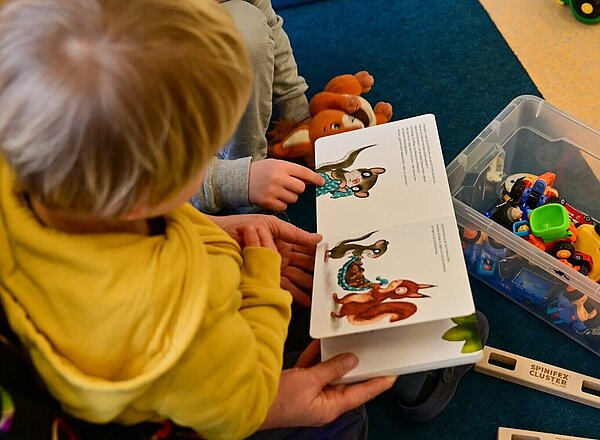 Kindergarten Eine Erzieherin liest mit zwei Kindern ein Buch.