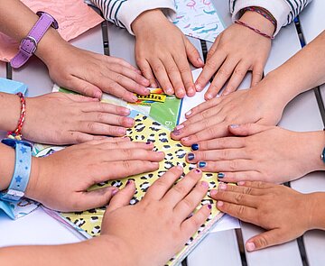 Karlsruhe spielt 2023 Kinder legen ihre Hände alle in die Tischmitte