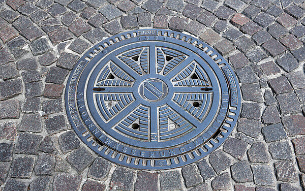 Stadtentwässerung Das Foto zeigt einen städtischen Schachtdeckel mit dem Logo der Stadt Karlsruhe.