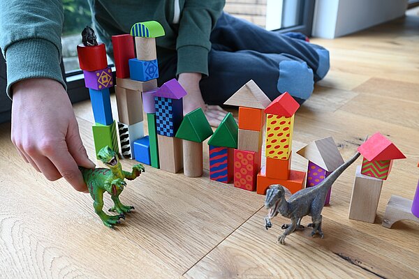 Bauklötze und Dino Bild spielt mit Dinosaurier und Bauklötzen.