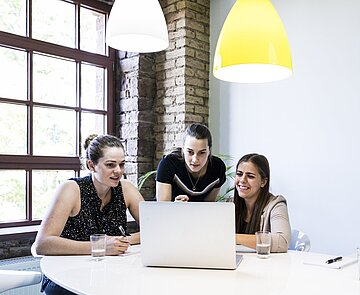 Studierende lernen gemeinsam Drei Studentinnen arbeiten im Team an einem Laptop.