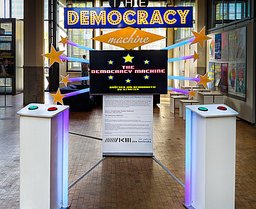 The Democracy Machine Im Las Vegas Stil: Große Tafeln mit The democracy machine. Drücken um Demokratie zu starten Aufschrift