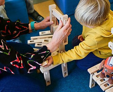Kindergarten Ein Kind baut etwas mit einer Erzieherin im Kindergarten.