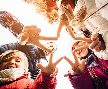Pflegekinder & Adoption Familie von unten fotografiert, formen mit ihren Fingern einen Stern.