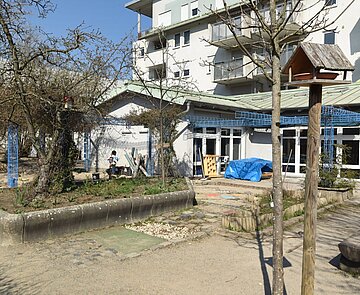 Kita Blücherstraße Gebäudeansicht Kindertagesstätte Blücherstraße mit Spielbereich draußen und Vogelhaus im Vordergrund