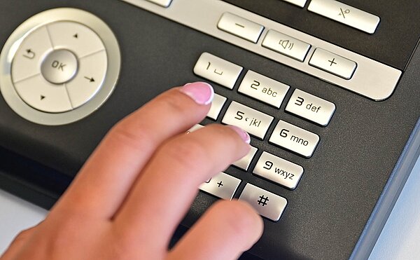 Ordnungsamt Notdienste Das Bild zeigt ein Telefon mit der Hand einer Person, die eine Notfallnummer wählt.