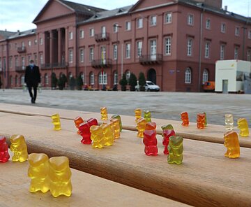Bank auf Marktplatz mit Gummibärchen Gummibärchen auf Bank als Symbol für leeren Marktplatz