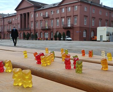 Bank auf Marktplatz mit Gummibärchen Gummibärchen auf Bank als Symbol für leeren Marktplatz