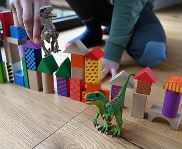 Bauklötze und Dino Bild spielt mit Dinosaurier und Bauklötzen.