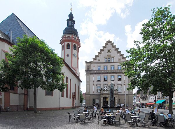 Stadtkirche Durlach Tische und Stühle stehen auf dem Marktplatz Durlach mit dem Kirchturm im Hintergrund.