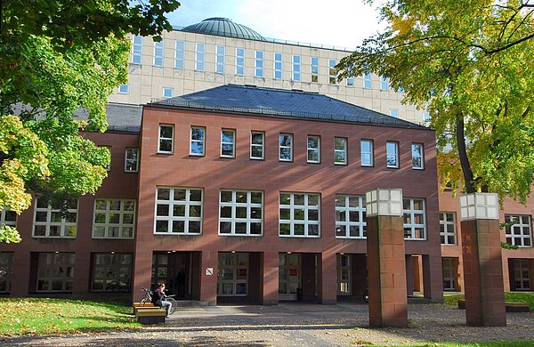Badische Landesbibliothek Der Eingang des Badischen Landesbibliothek eingerahmt von Bäumen.