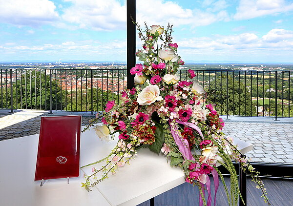 Blumengesteck und lederne Traumappe auf Tisch.