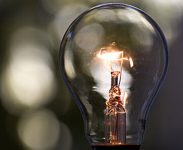 Das Symbild zeigt eine sanft leuchtende Glühbirne.