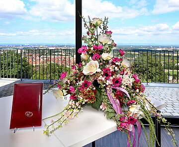 Blumengesteck und lederne Traumappe auf Tisch.