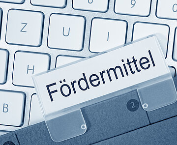 Tatstatur mit einer Akte auf der Fördermittel steht.