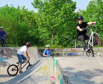 Das Bild zeigt Jugendliche mit ihren Fahrrädern auf dem Parcour des Skateplatzes in der Günther-Klotz-Anlage.