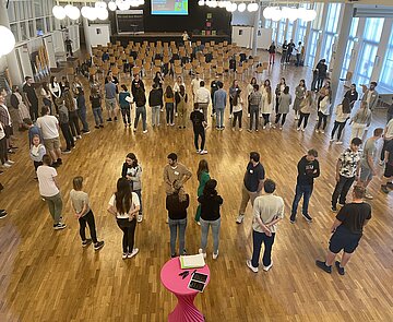 Auszubildenden von schräg oben. Sie stehen in einem Kreis und reden miteinander