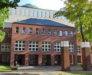 Der Eingang des Badischen Landesbibliothek eingerahmt von Bäumen.