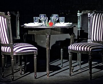 Zwei Stühle und ein gedeckter Tisch stehen in einem Raum. 