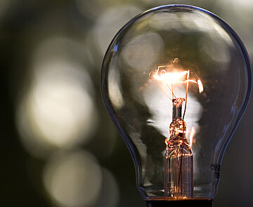 Das Symbild zeigt eine sanft leuchtende Glühbirne.