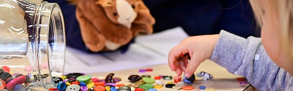 Kinderhände spielen mit Knöpfen.