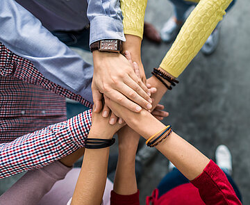 Foto von mehreren Händen, die miteinander einschlagen.