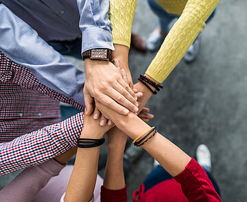 Foto von mehreren Händen, die miteinander einschlagen.
