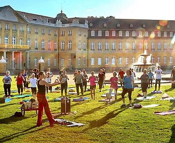 Personen bei Sportübungen vor dem Schloss Karlsruhe