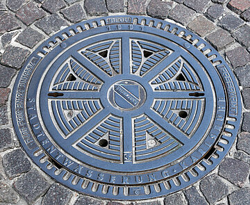 Das Foto zeigt einen städtischen Schachtdeckel mit dem Logo der Stadt Karlsruhe.