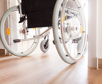 Das Bild zeigt einen rollstuhlfahrenden Mensch, der durch Türrahmen fährt.