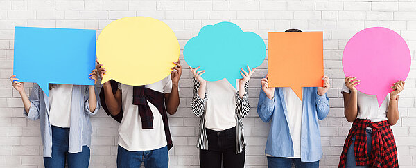 Teenager halten Sprechblasen aus bunten Papier vor ihre Gesichter