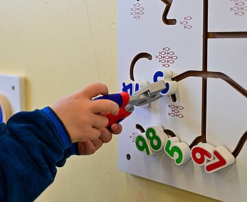 Ein Kind spielt an einem Motorikboard.