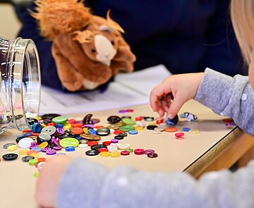 Kinderhände spielen mit Knöpfen.