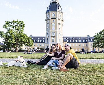 Das Bild zeigt Studierende mit einem Hund im Schlossgarten.