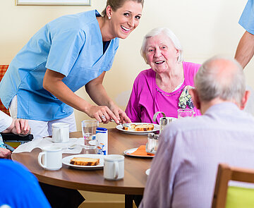 Gruppe von älteren Menschen sitzen am Tisch im Pflegeheim.