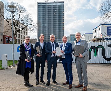 Bürgermeister Daniel Fluhrer (2.v.r.) übergibt die Baugenehmigung der Stadt Karlsruhe für den Neubau auf dem Landratsamt-Areal an Landrat Dr. Christoph Schnaudigel (3.v.l.). Mit dabei sind Ragnar Watteroth, Finanzdezernent des Landkreises (r.) sowie Monika Regner und Andreas Fischer vom Bauordnungsamt der Stadt Karlsruhe.