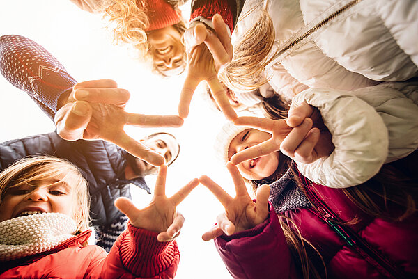 Familie von unten fotografiert, formen mit ihren Fingern einen Stern.