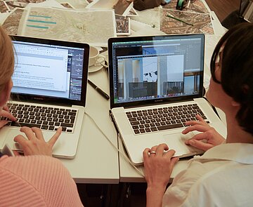 Zwei Personen an Laptops