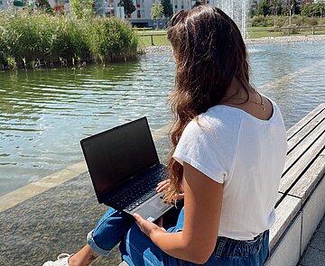 Mädchen im Park mit Laptop auf dem Schoß