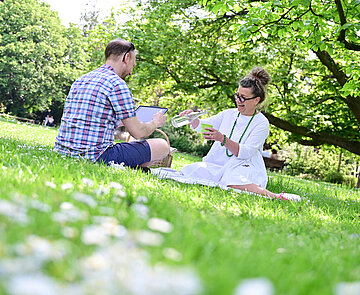 Zwei Personen sitzen auf einer Wiese im Park.