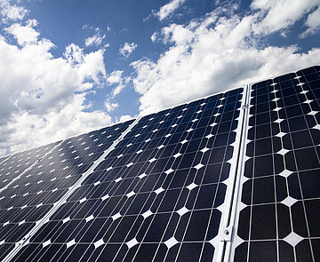 Das Symbolbild zeigt ein Solarpanel vor blauem Himmel mit Wolken.