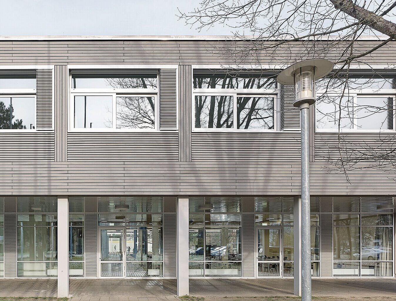 Zu sehen ist eine Detailaufnahme der grau lasierten Holzfassade und der neuen Fensterelementen.