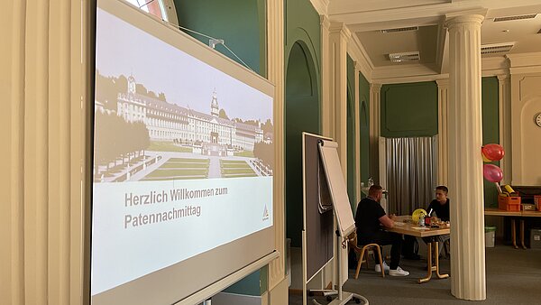 Beamerleinwand mit Motiv des Karlsruher Schloss steht in einem Raum.