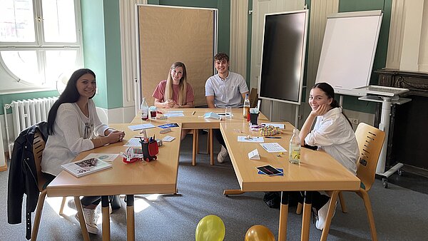 Mehrere Personen sitzen in einem Raum an Tischen.